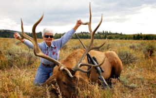 woman posing with elk and horns