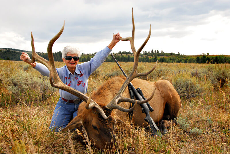 woman posing with elk and horns