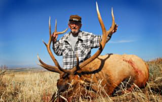 man posing with elk and horns