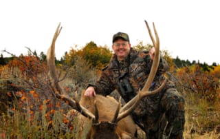 man posing with elk and horns