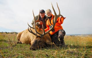 man & woman posing with elk and horns