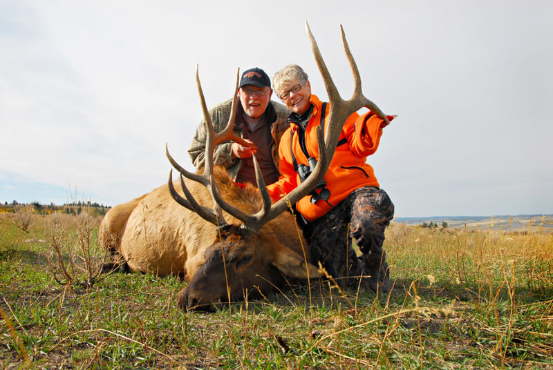 man & woman posing with elk and horns