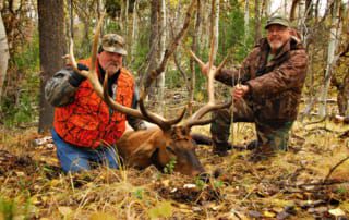 two men posing with elk and horns