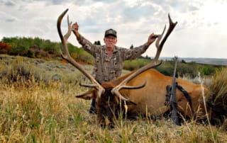 man posing with elk and horns