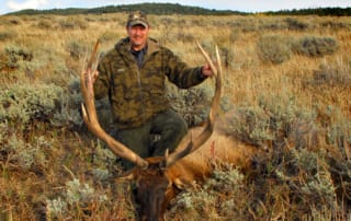 man posing with elk and horns