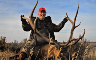 man posing with elk and horns