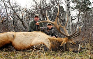 man and young boy posing with elk and horns