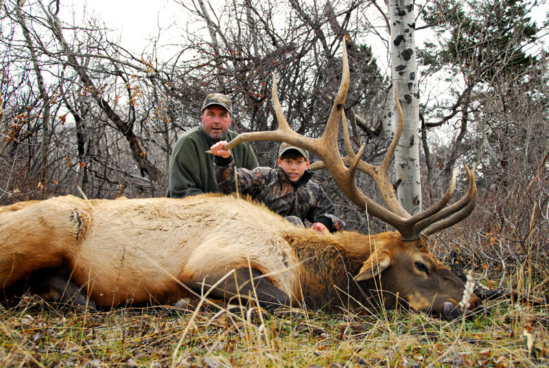 man and young boy posing with elk and horns