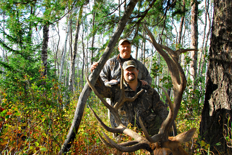 two men posing with elk and horns