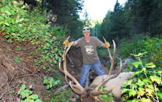 man posing with elk and horns