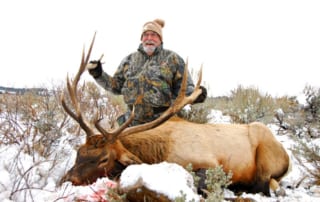 man posing with elk and horns in winter