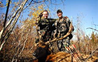 two men posing with elk and horns