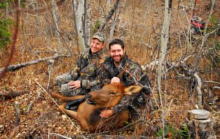 two men posing with elk