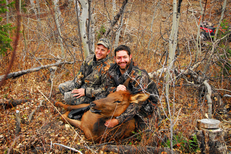 two men posing with elk