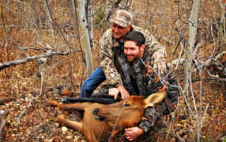 two men posing with elk