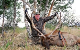 man posing with elk and horns