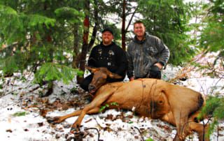 two men posing with elk