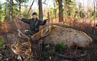 young man posing with elk and horns