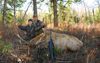 man and son posing with elk and horns