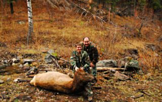 two men posing with elk