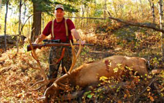 man posing with elk and horns