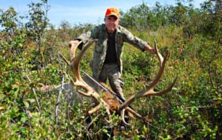 man posing with elk and horns