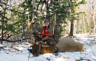 young man posing with elk and horns