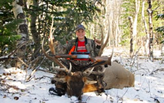 young man posing with elk and horns