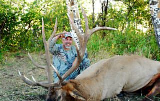 man posing with elk and horns