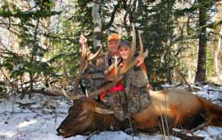 man and woman posing with elk and horns