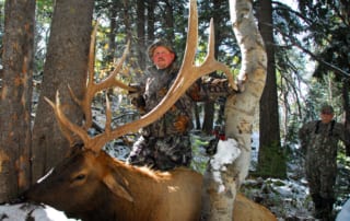 man posing with elk and horns