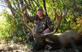 man posing with elk and horns