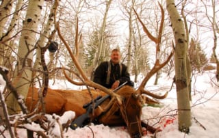 man posing with an elk and horns