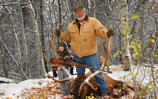 man and child posing with an elk and horns