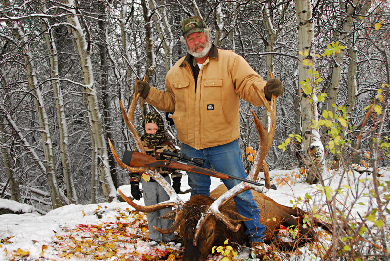 man and child posing with an elk and horns