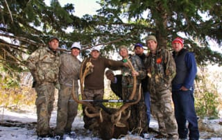 group posing with an elk and horns