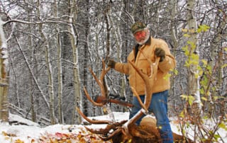 man posing with an elk and horns