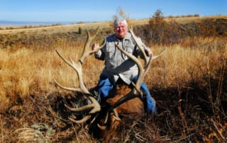 man posing with an elk and horns