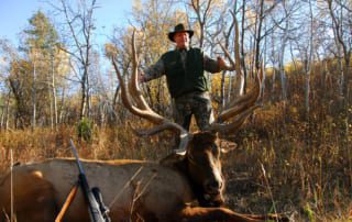 man posing with an elk and horns