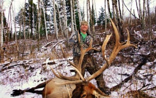 man posing with an elk and horns