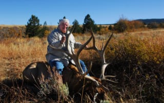 man posing with an elk and horns