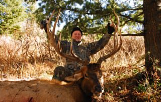 man posing with an elk and horns