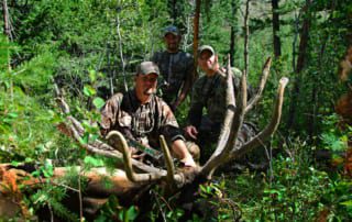 two men posing with elk and horns