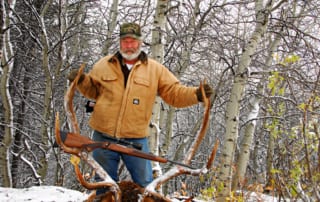 man posing with an elk and horns