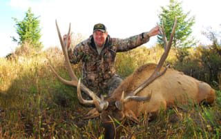 man posing with an elk and horns