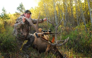 man posing with an elk and horns