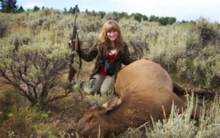 woman posing with an elk and horns