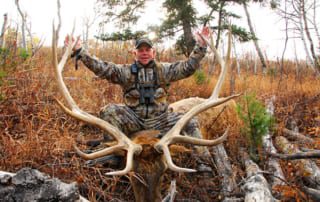 man posing with an elk and horns