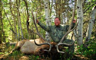 man posing with an elk and horns