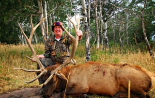 man posing with an elk and horns